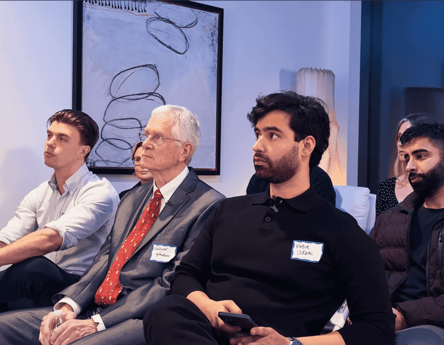 Kabir Israni seated in the audience at an event, beside Raveum director Glenn Hanson